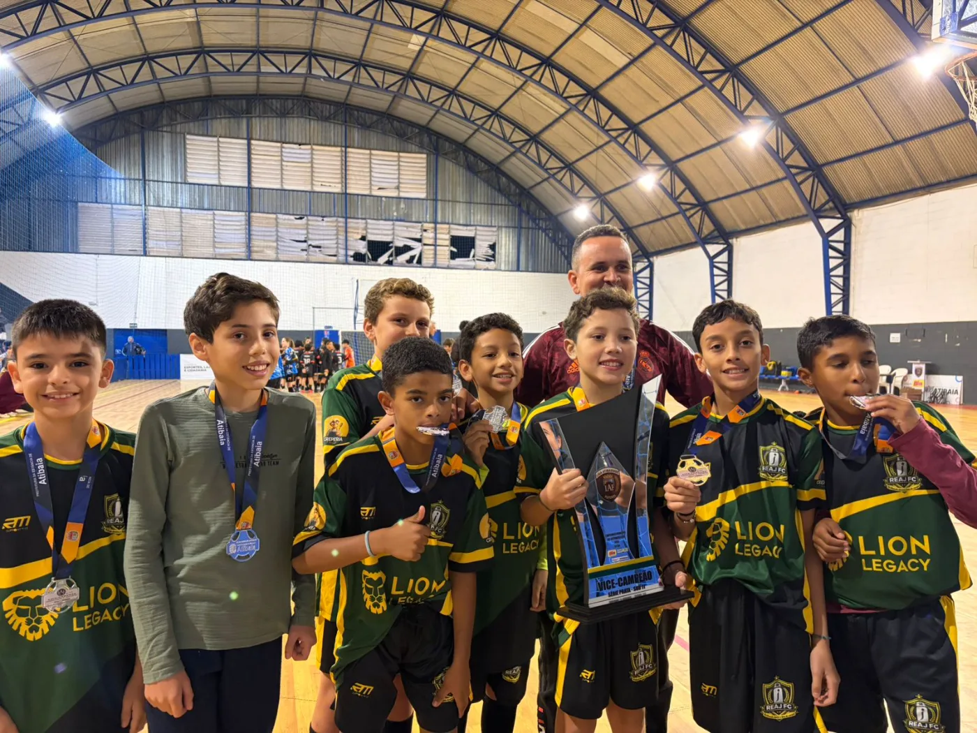 REAJ Futebol Club — atletas com medalhas e troféu